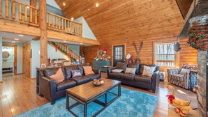 A spacious living room with wooden ceilings and a high ceiling, furnished with leather sofas and a coffee table. - Woodsy Retreat Near Wisp w/ Golf & Hot Tub (McHenry)