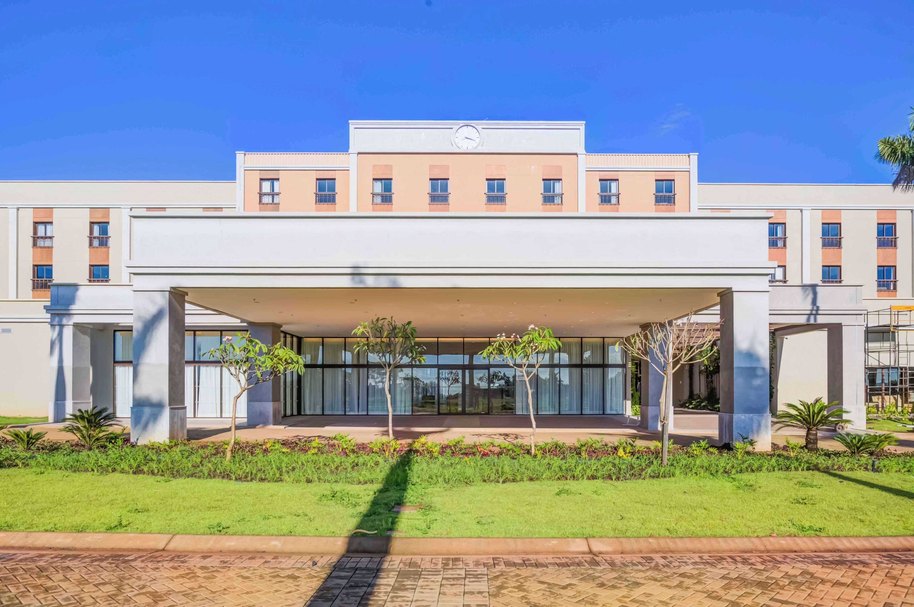 Un hôtel moderne doté d’une entrée couverte, de plusieurs étages et d’une horloge sur la façade.