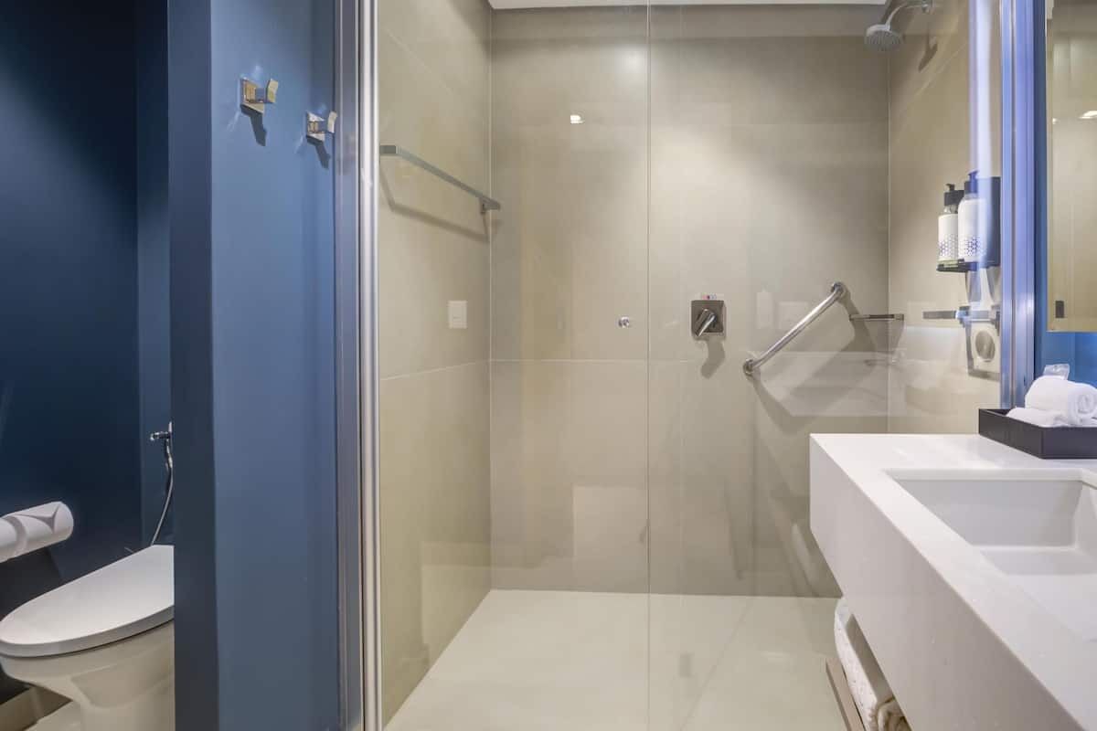 A modern bathroom with a glass-enclosed shower, a white sink, and a blue accent wall.