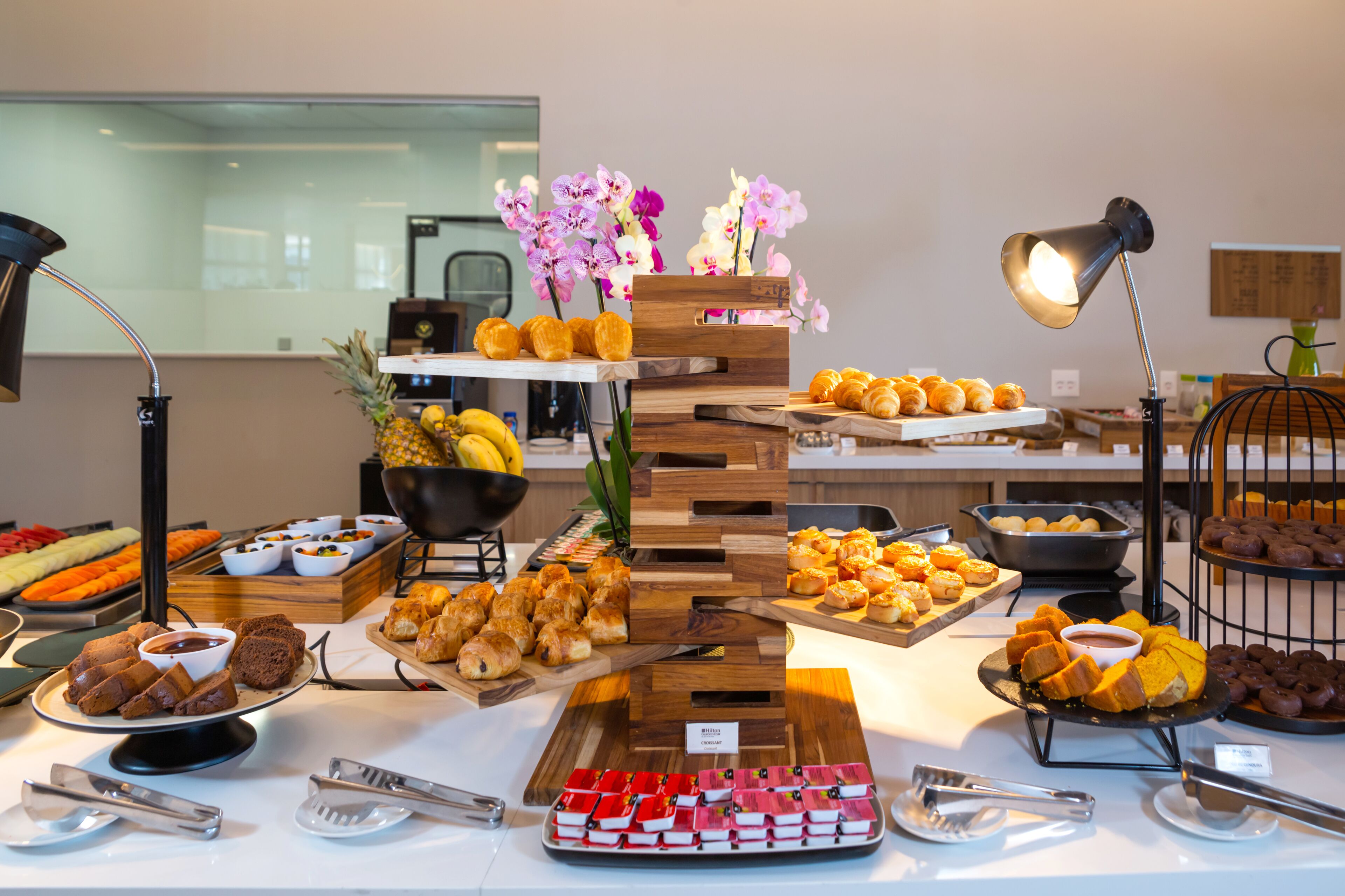 A buffet with various food items and a decorative wooden stand with flowers.