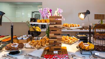 A buffet with various food items and a decorative wooden stand with flowers.