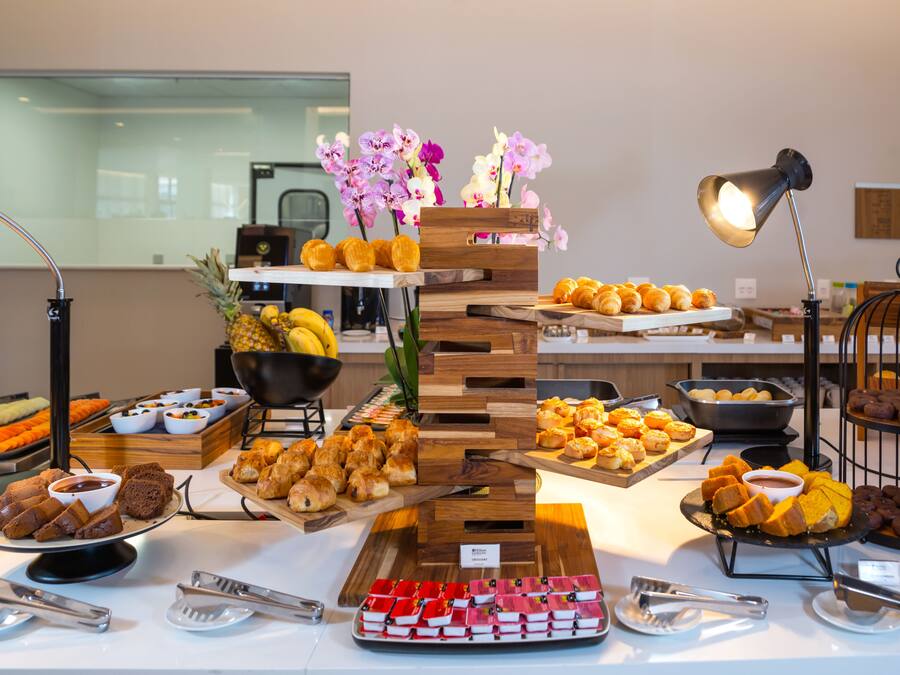 A buffet with various food items and a decorative wooden stand with flowers.