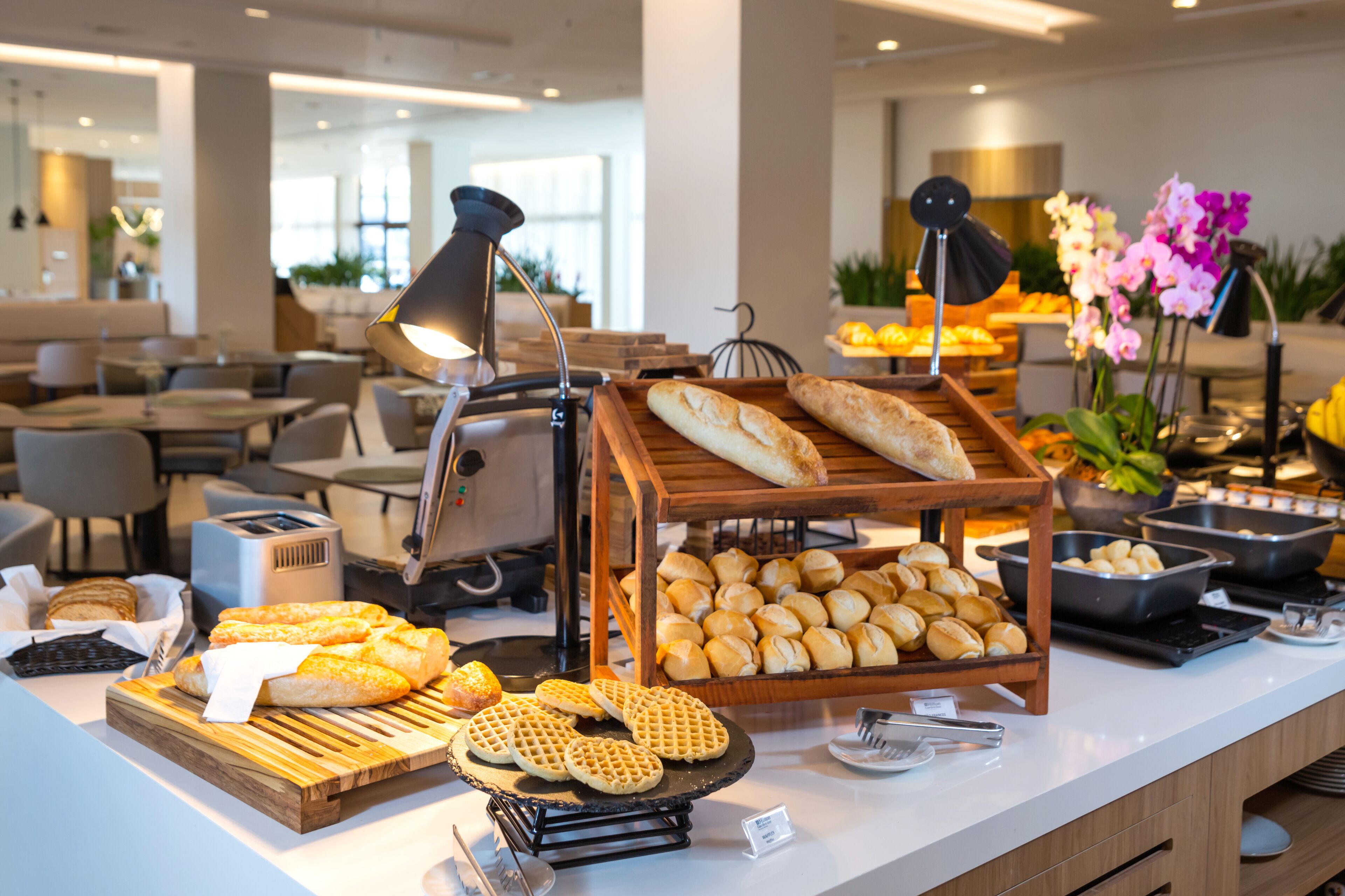 A buffet with various breads, waffles, and pastries.