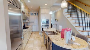A modern kitchen with stainless steel appliances, a marble countertop, and a built-in oven. - Lavish Oceanfront Townhome- Whispering Palms (Folly Beach)