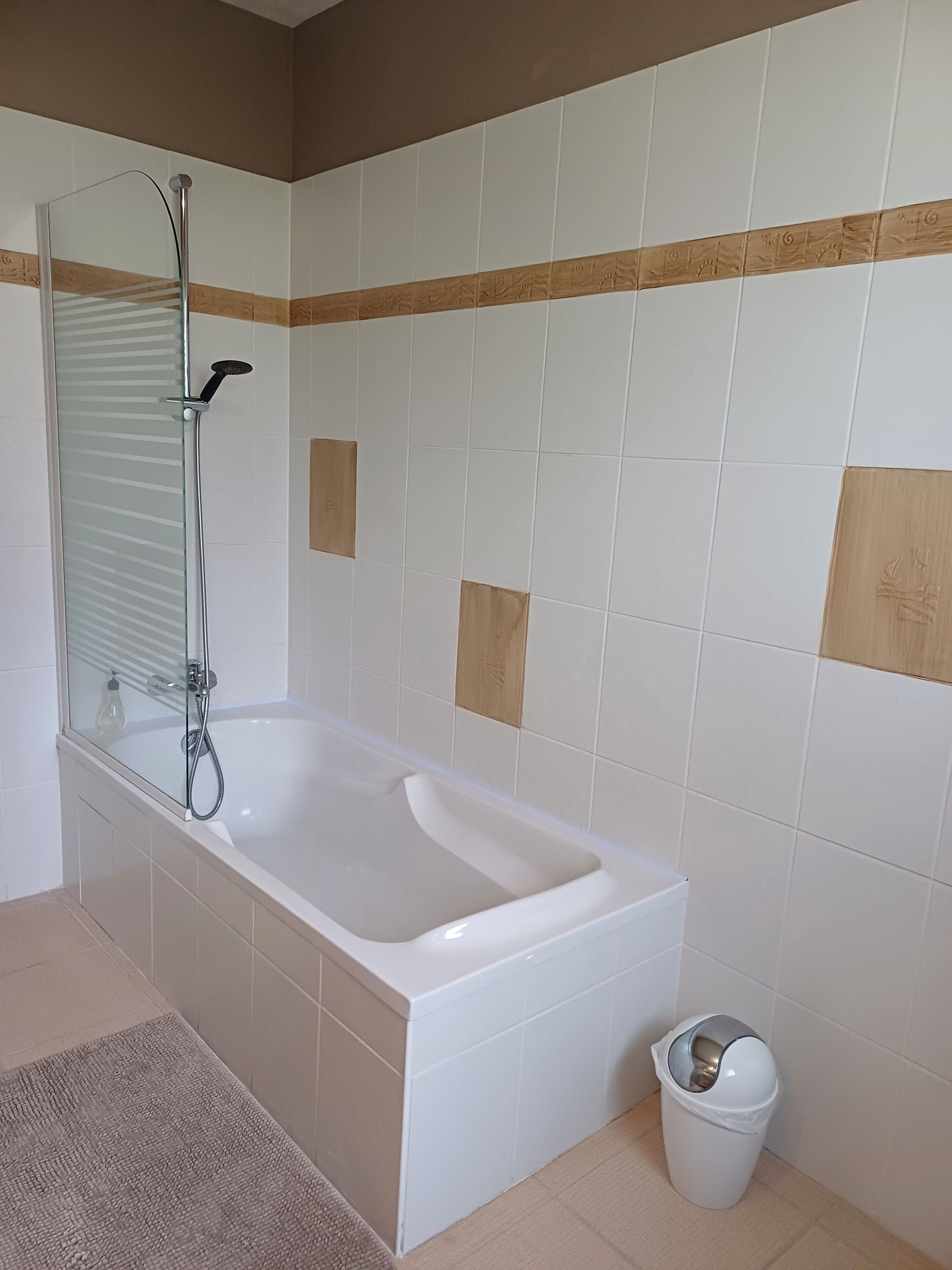 Ein Badezimmer mit Badewanne, Duschkabine und Mülleimer.