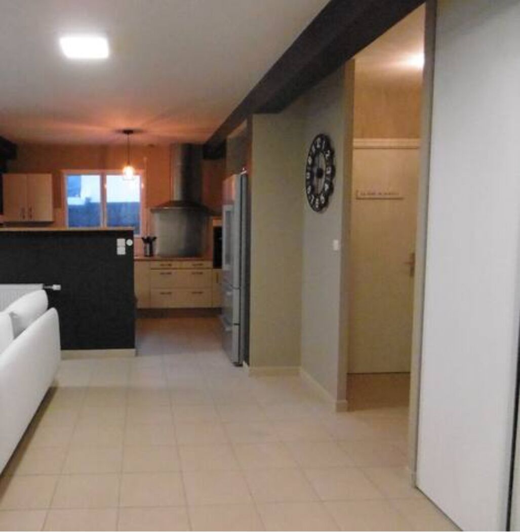 Une cuisine moderne avec un îlot central, un réfrigérateur et une horloge au mur.