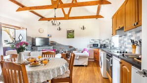 A cozy kitchen with wooden beams, a dining area with a table set for breakfast, and a stone fireplace. - 2 Bed cottage, log burner. Pet friendly - 5 mins to nearest beach. (Port Isaac)