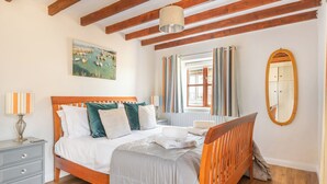 A bedroom with a wooden bed, a nightstand, a dresser, a window with curtains, and a mirror. - 2 Bed cottage, log burner. Pet friendly - 5 mins to nearest beach. (Port Isaac)