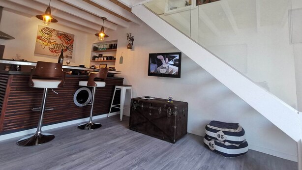 A modern kitchen with a wooden ceiling, a bar area with stools, and a staircase leading to an upper level. - Ultra cosy small house (Piriac-sur-Mer)
