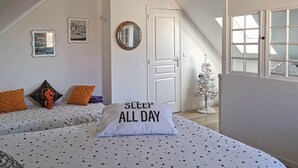 A bedroom with two beds, a white door, a small Christmas tree, and a pillow with "SLEEP ALL DAY" text. - Ultra cosy small house (Piriac-sur-Mer)