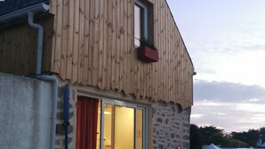 A wooden building with a glass door, a small outdoor seating area, and a flag. - Ultra cosy small house (Piriac-sur-Mer)