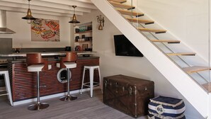 A modern kitchen with a bar area, a staircase, and a vintage suitcase. - Ultra cosy small house (Piriac-sur-Mer)