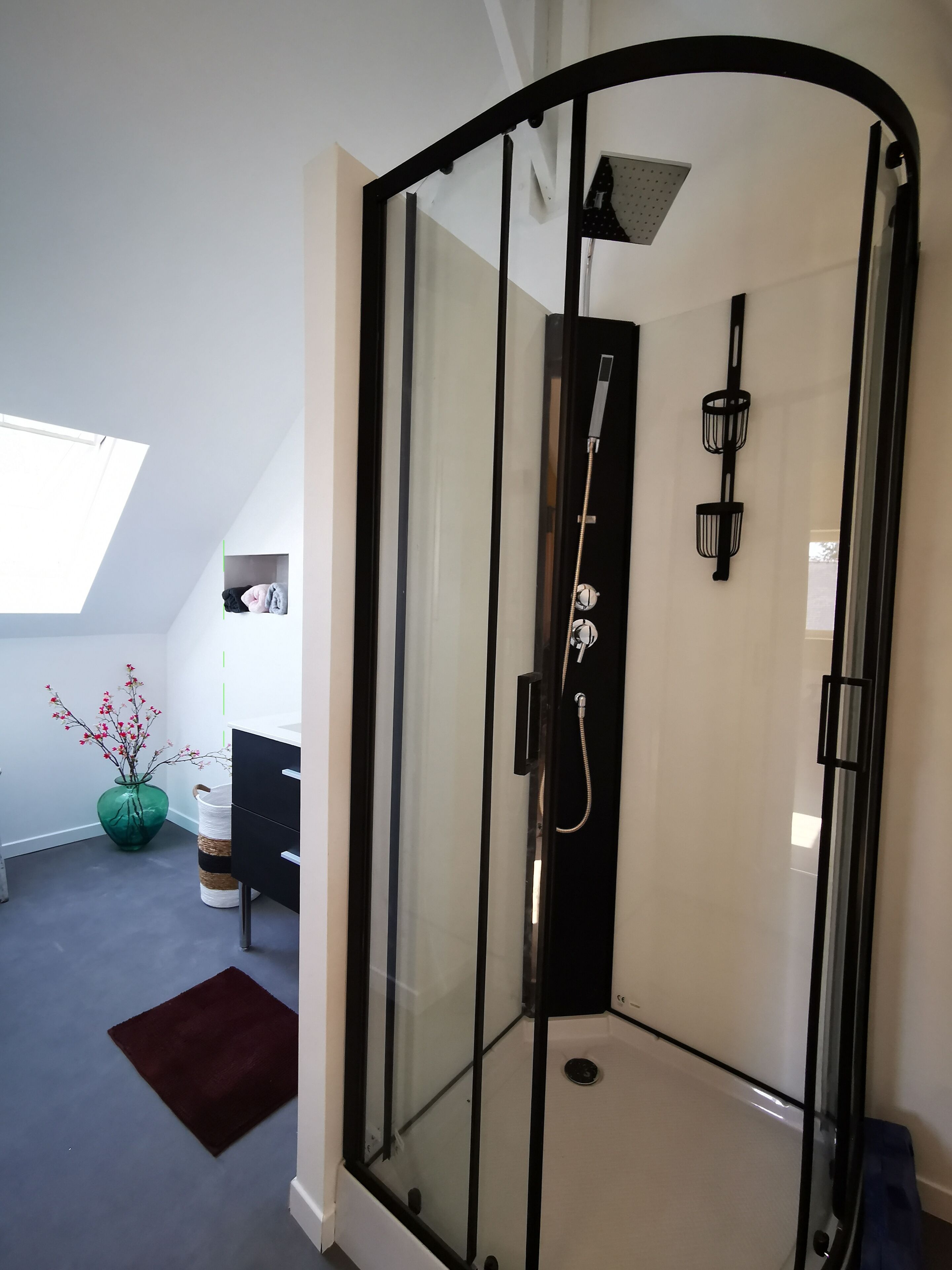 Eine moderne Duschkabine mit Glastür, Handtuchhalter und einem kleinen Fenster.