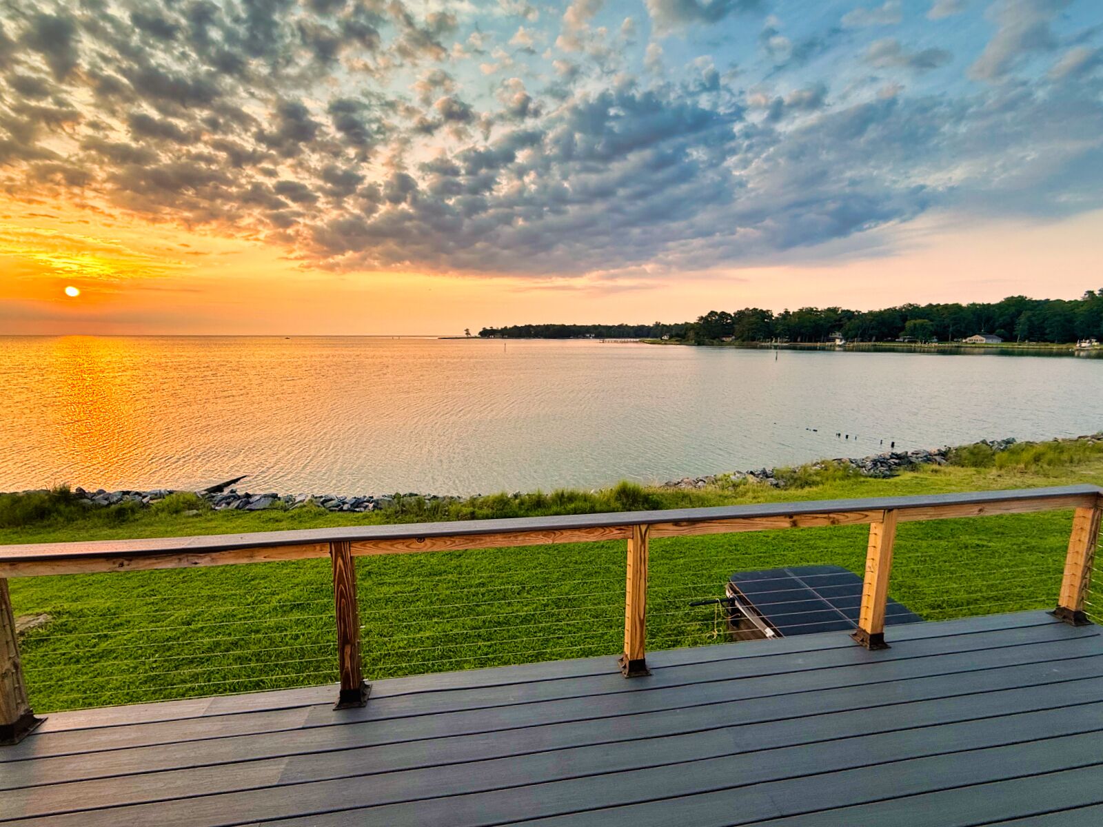 A deck overlooking a lake with a sunset.