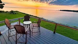 En terrasse med udendørs siddepladser med udsigt over vandet i solnedgang.