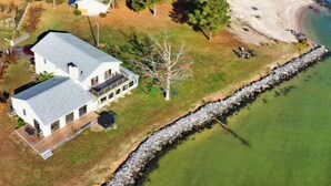 An aerial view of a coastal property with a large house, a beach, and a body of water.