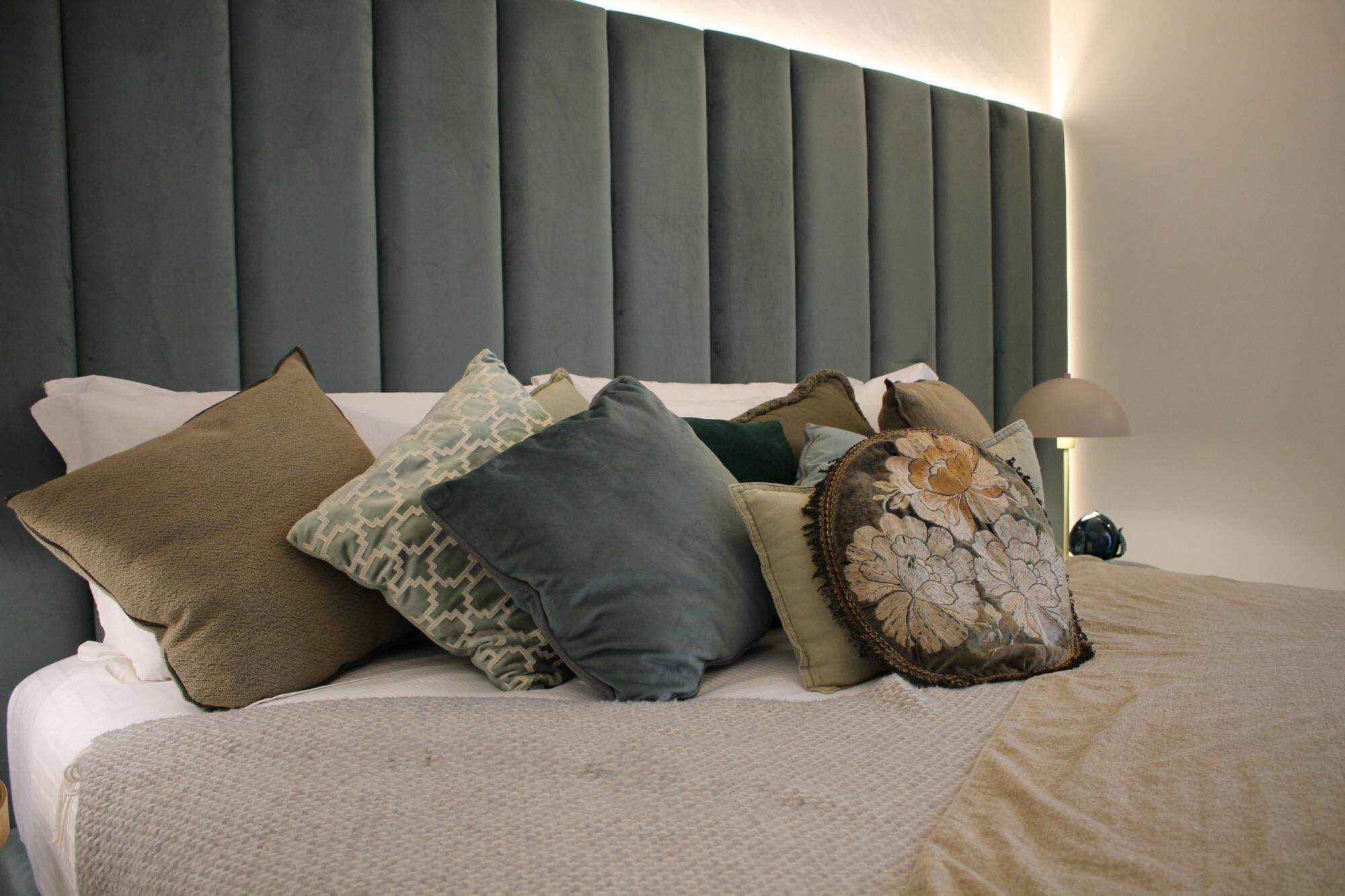 Una cama con muchos almohadones y un cabecero.