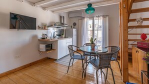 A compact kitchen with a microwave, kettle, and a small dining area with wicker chairs and a glass table. - Sant Onofrio Mini Loft by Wonderful Italy (Palermo)