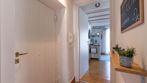 A hallway leading to a kitchen with a chalkboard sign, a phone, and a shelf with plants. - Sant Onofrio Mini Loft by Wonderful Italy (Palermo)