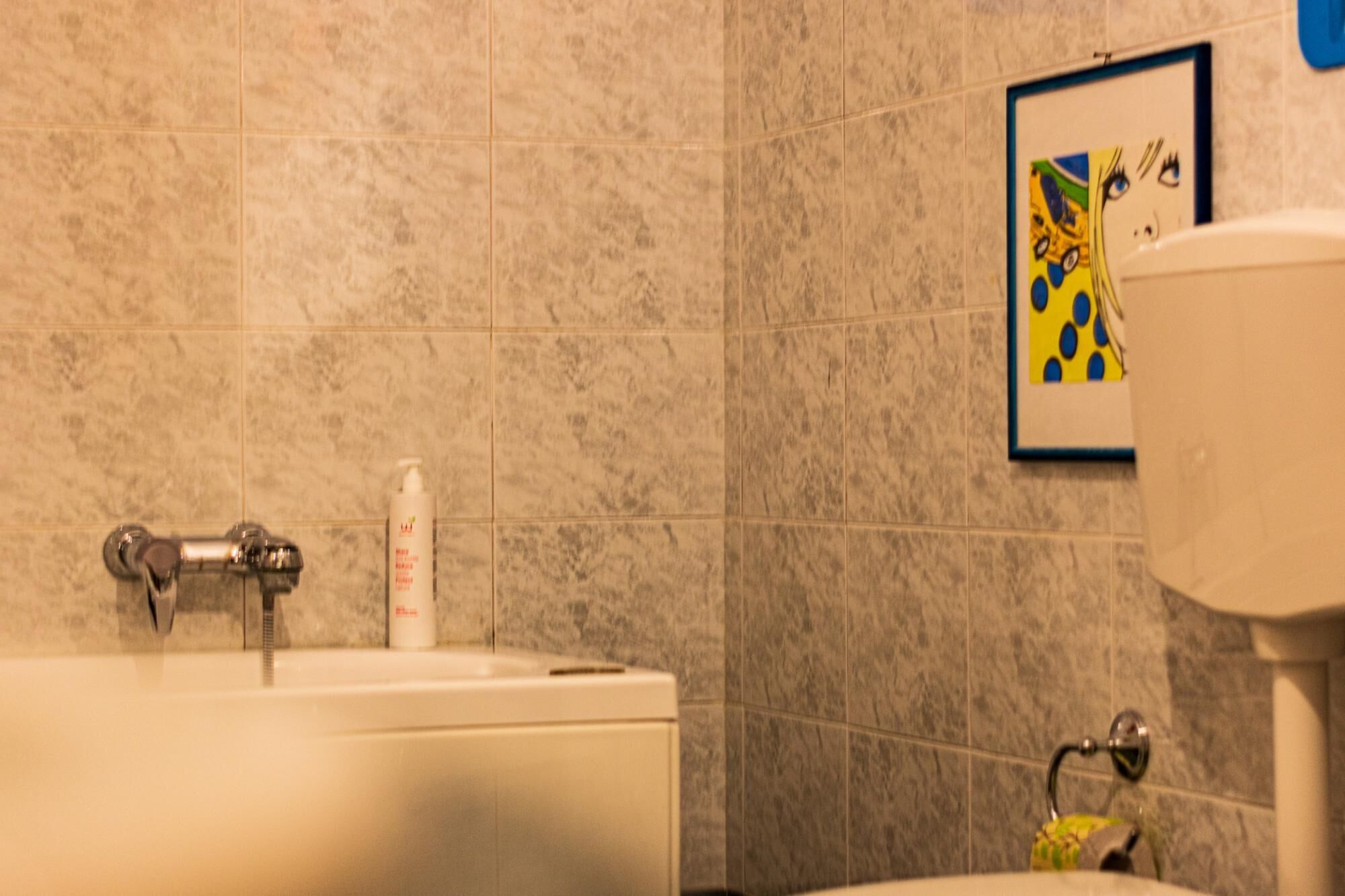 A bathroom with a bathtub, a toilet, and a framed artwork on the wall.
