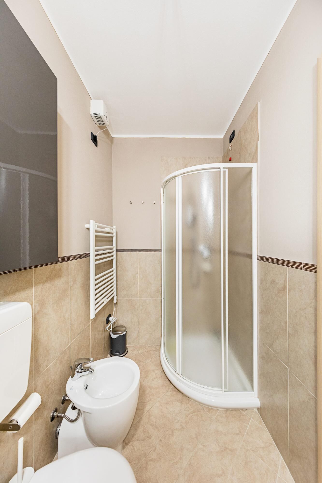 A modern bathroom with a toilet, bidet, and a glass-enclosed shower.