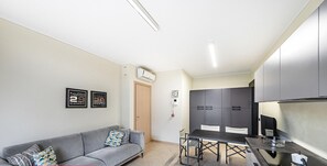 Ein kompakter Wohnbereich mit Sofa, Esstisch und Küchenzeile.