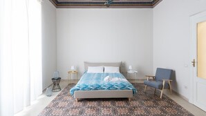 A bedroom with a bed, a chair, a nightstand, and a decorative ceiling. - Casa Darsena With Sea View Balcony by Wonderful Italy (Syracuse)