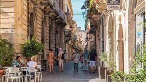 A narrow street lined with cafes and outdoor seating, with people walking and sitting. - Casa Darsena With Sea View Balcony by Wonderful Italy (Syracuse)