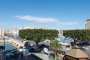 A waterfront street with buildings, trees, and parked cars. - Casa Darsena With Sea View Balcony by Wonderful Italy (Syracuse)