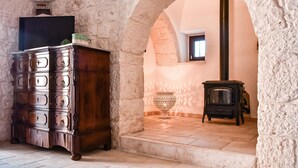 A stone-walled room with a wooden dresser, a small table, and a fireplace. - Borgo S Clara - Esterina by Wonderful Italy (Cisternino)