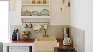A kitchen with white cabinets, a sink, a kettle, and a coffee machine.