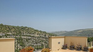 A balcony with a metal railing overlooking a hilly landscape with sparse vegetation. - Casa Ibla Duplex con Terrazza by Wonderful Italy (Ragusa)