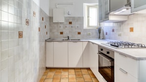 A modern kitchen with white cabinets, a stainless steel sink, and a gas stove. - Castiglione Family Apartment by Wonderful Italy (Bologna)