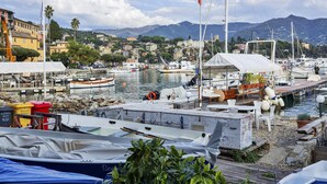 A marina with boats docked, a white tent, and a mountainous backdrop.