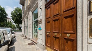 Un bâtiment doté d’une grande porte double en bois, d’un trottoir et de voitures garées.