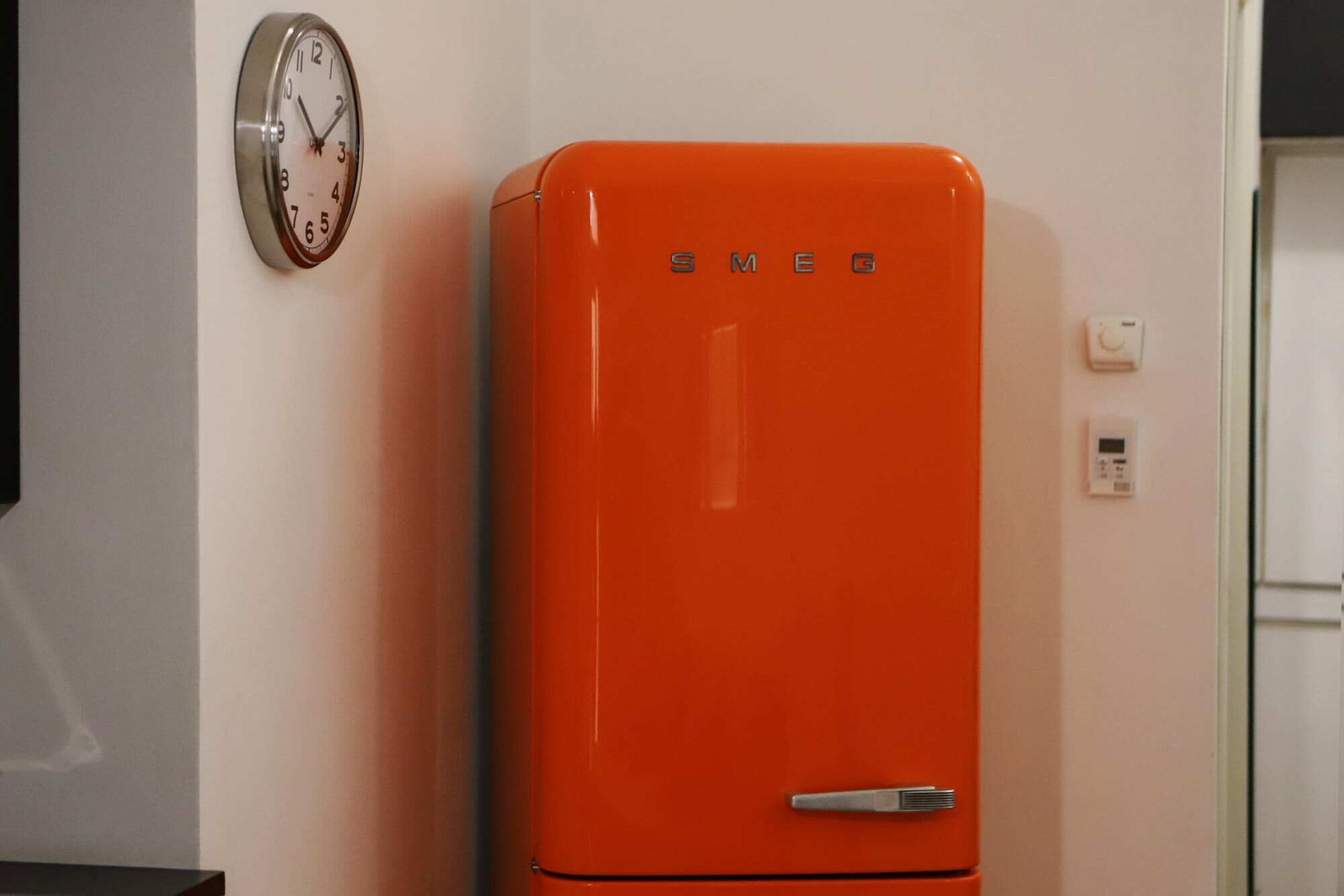 A bright orange refrigerator with the brand name 'SMEG' on the top.