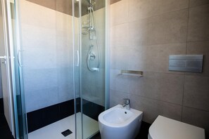 A modern bathroom with a glass-enclosed shower, a bidet, and a toilet. - Le Terrazze sui Tetti di Noto by Wonderful Italy (Noto)