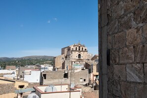 A view of a historic building with a bell tower, surrounded by residential buildings and a hilly landscape in the background. - Le Terrazze sui Tetti di Noto by Wonderful Italy (Noto)