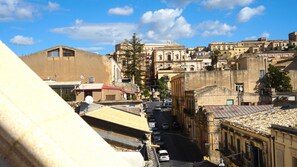 A street view with buildings, cars, and a clear sky. - Le Terrazze sui Tetti di Noto by Wonderful Italy (Noto)
