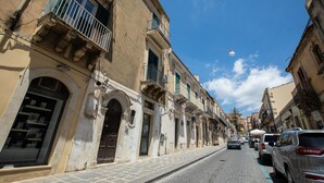A street with historic buildings, a clear blue sky, and parked cars.