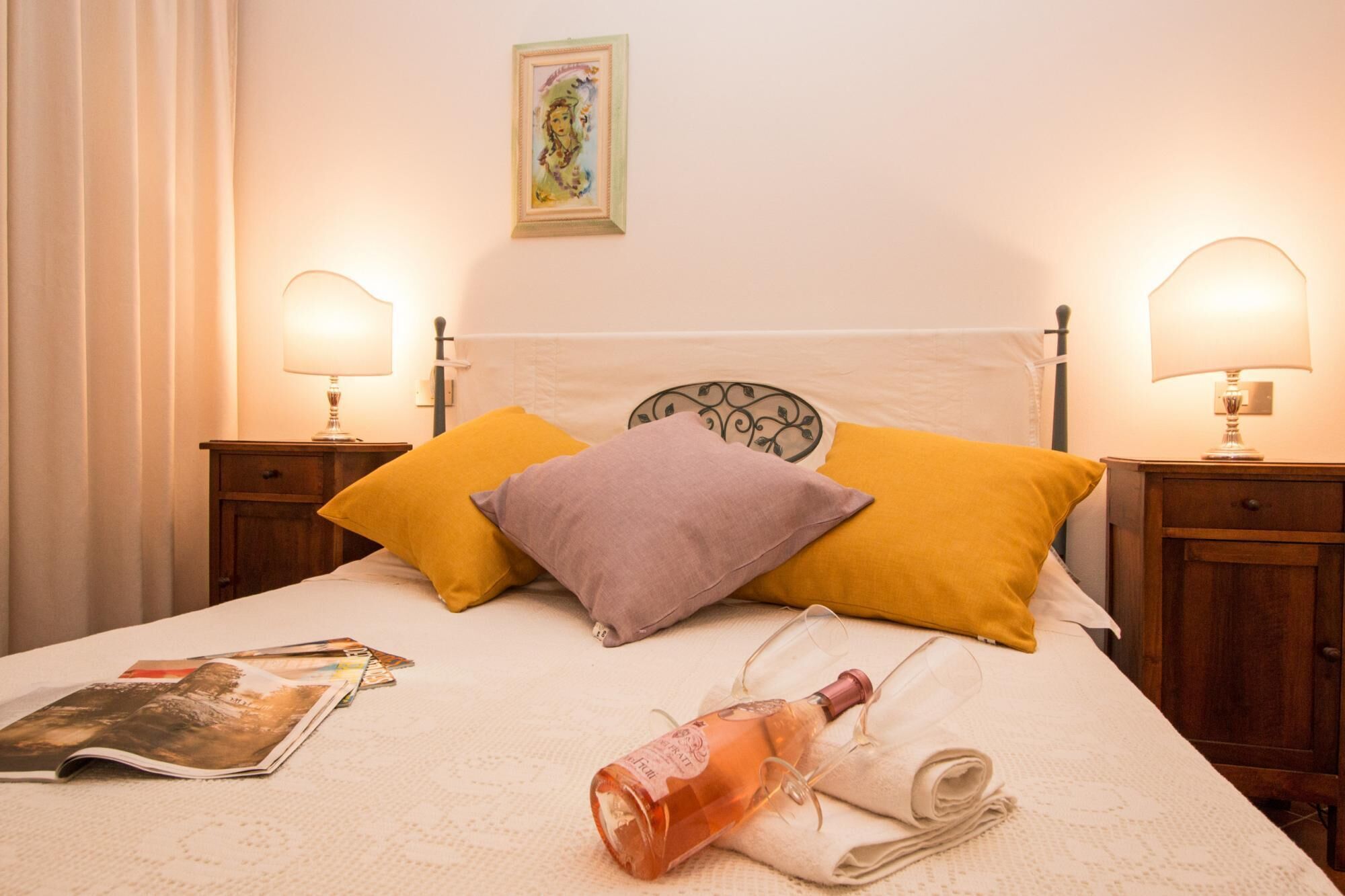 A neatly made bed with a headboard, two bedside lamps, and a few pillows.