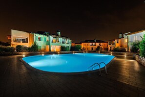 Una piscina rodeada de edificios de noche.