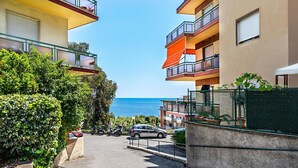A residential building with multiple balconies, a paved driveway, and a view of the sea. - Le Orchidee 19 by Wonderful Italy (Sanremo)
