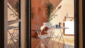 An outdoor patio with a table, chairs, and potted plants.