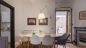 A dining area with a round table, white chairs, a lamp, and framed pictures on the wall.