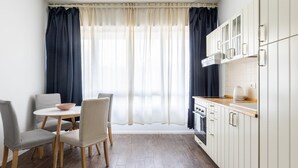 Eine moderne Küche mit weißen Schränken, einer Holzausziehtheke und einem Essbereich mit rundem Tisch und Stühlen.