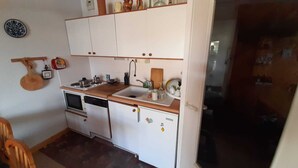 Een praktische keuken met witte kastjes, een houten aanrecht, een spoelbak, een kookplaat en een vaatwasser.