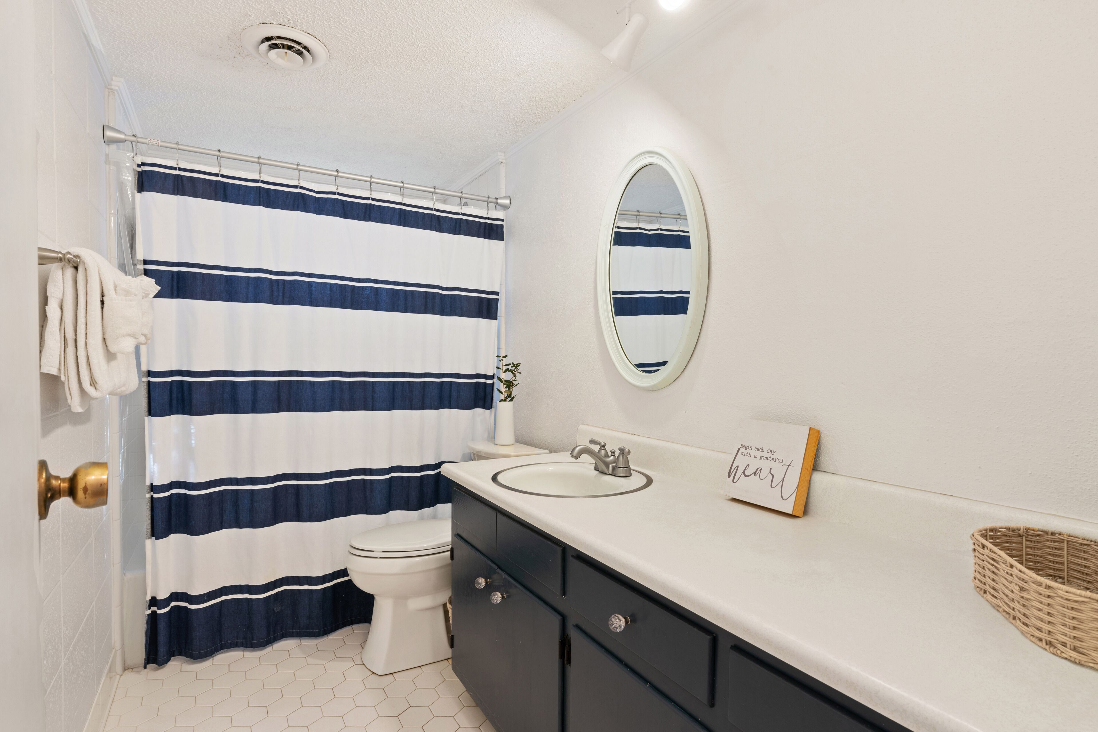 A bathroom with a striped shower curtain, a toilet, a sink, and a mirror.