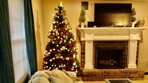 A cozy living room with a fireplace, a Christmas tree, and a television on the mantel. - 5 Star Location (Springfield)