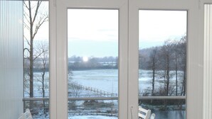 A room with a view of a snowy landscape through large windows. - Eckhorst Farm, Ruhwinkel (Güby)